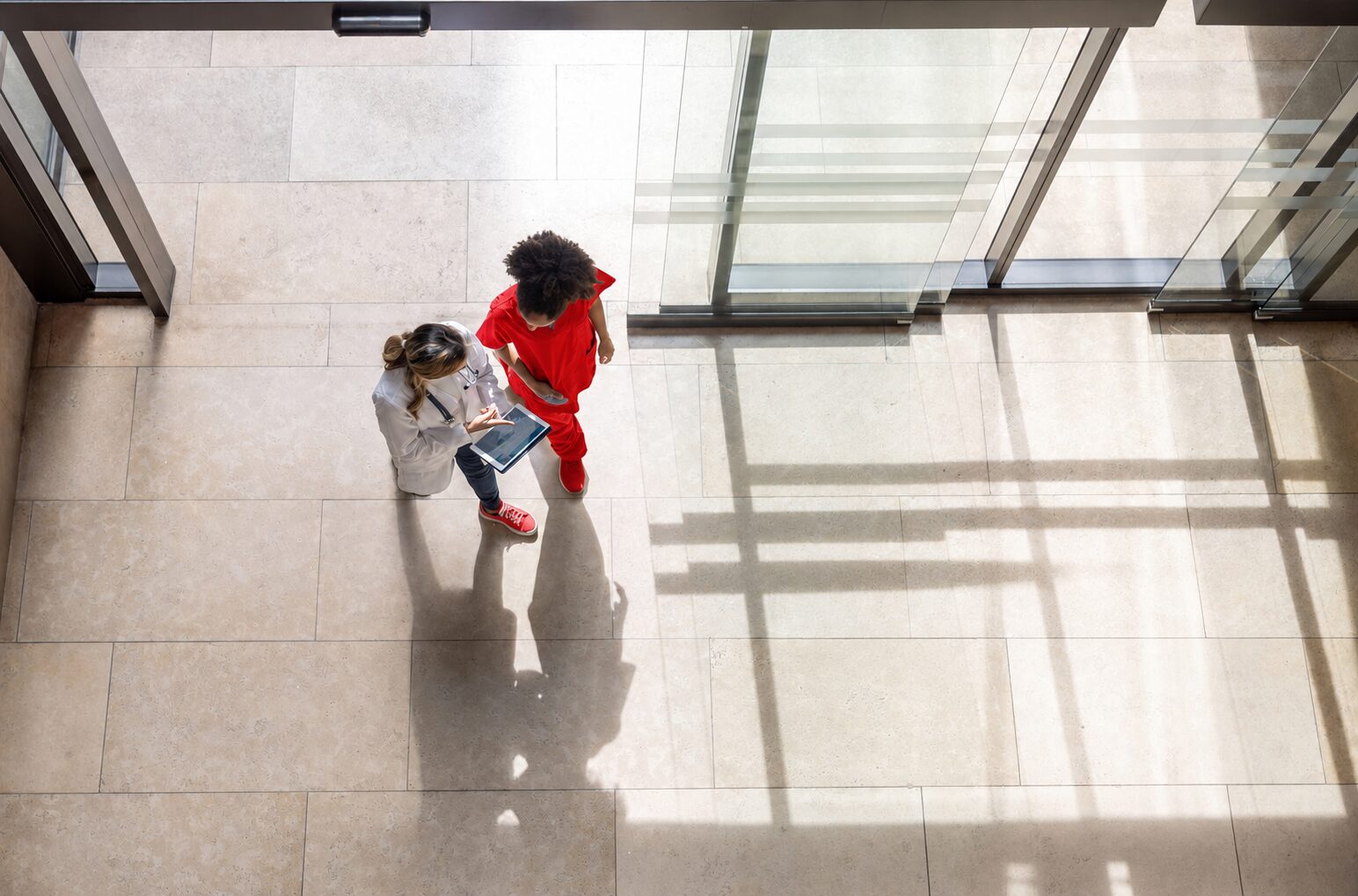Birds eye view of Two Women in Hospital WALKING past access control vestibule - solucient security detroit chicago